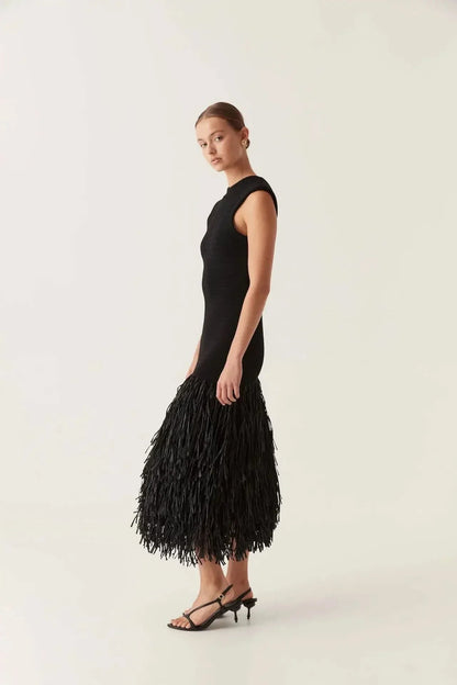 Black midi dress side view showing fitted ribbed knit bodice and tiered fringe skirt detail