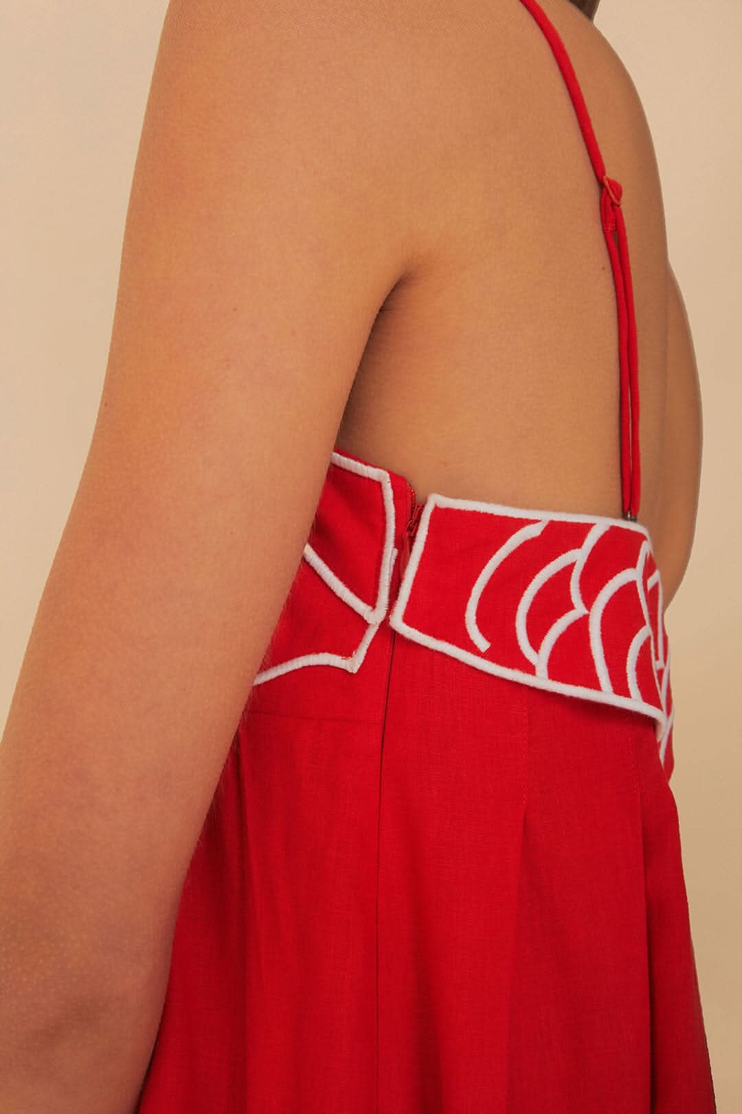 Close-up of white fish print embroidery on red maxi dress bodice
