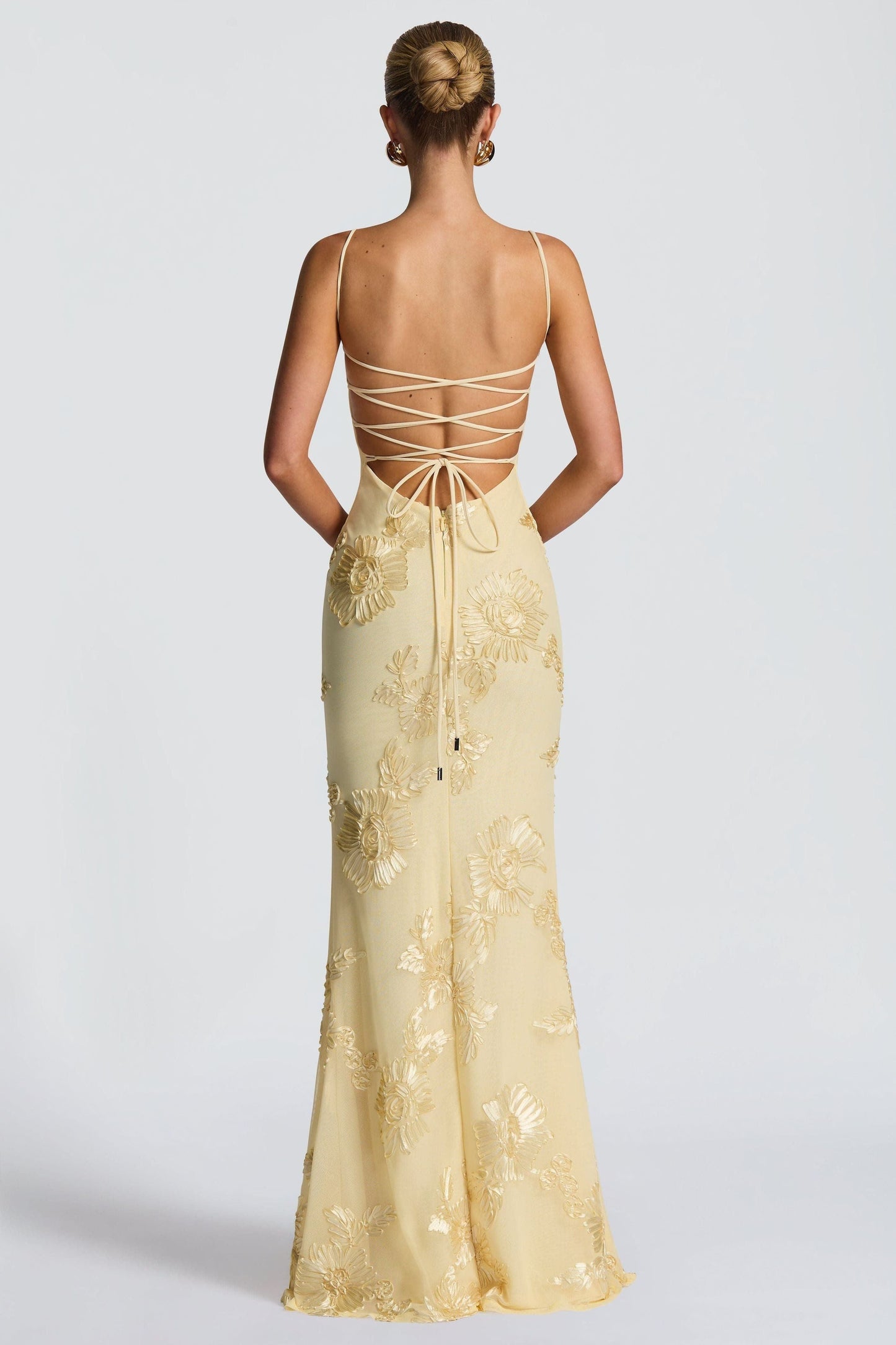 Back view of cream maxi dress with lace-up strappy back and gold floral details