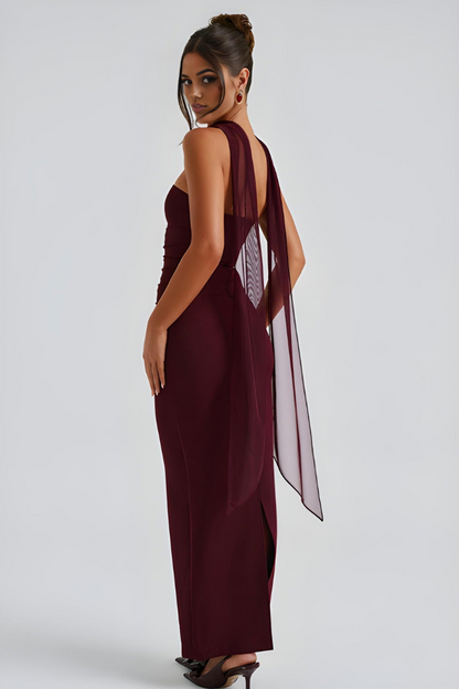 Side view of burgundy strapless maxi dress with draped sheer scarf accent