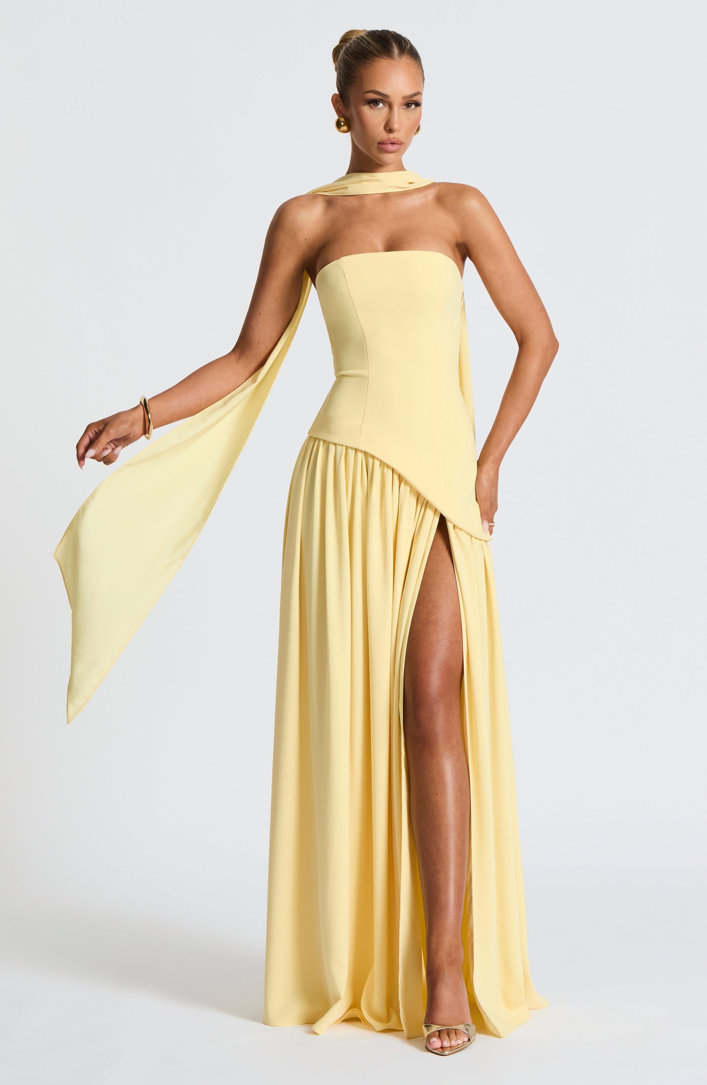 Pale yellow strapless maxi dress with flowing draped fabric and side slit